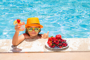 Little child by the pool eating fruit and drinking lemonade cocktail. Summer kids vacation concept.