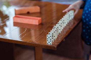 Boy playing with dominoes, close up. Build a domino fence, close up