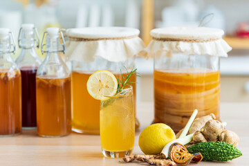 Herbal drink. Kombucha tea with lemon and sweetened root filling in glass jug on kitchen background.
