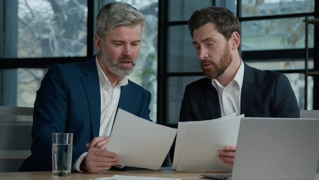 Caucasian mature businessmen checking documents sales research project in office comparing paperwork discussing strategy colleagues entrepreneurs analyze report discuss business plan Generative AI