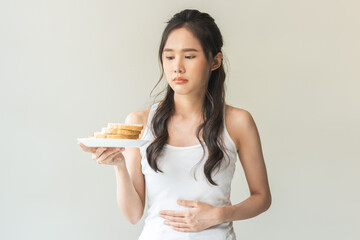 Gluten allergy, asian young woman hand holding, refusing to eat, looking at bread slice on plate in breakfast food meal at home, having a stomach ache. Gluten intolerant and Gluten free diet concept.