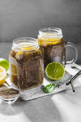 Chia Infused Water with Lemon and Lime in Jars, Healthy Citrus Drink on Bright Background