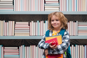 School boy with books in library. Little student school child. Portrait of nerd student with school supplies.