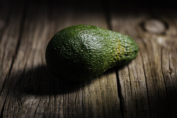 One Avocado Fruit on Rustic Wooden Table and Dramatic Mood. Stock Photo