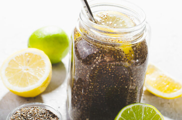 Chia Infused Water with Lemon and Lime in Jars, Healthy Citrus Drink on Bright Background
