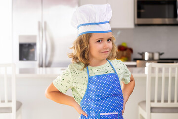 Funny child stand at kitchen table have fun baking, doing bakery preparing food at home kithen.