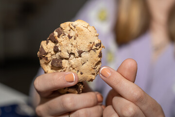 cookie au chocolat dans les mains d'une jeune fille faisant un coeur avec ses doigts
