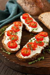 Cream cheese  with tomatoes cherry on  slice of rye bread  on wooden table