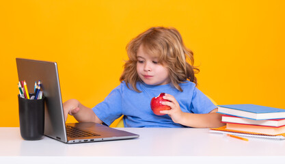 School child using laptop computer. Nerd school kid isolated on studio background. Clever child from elementary school with book. Smart genius intelligence kid ready to learn. Hard study.