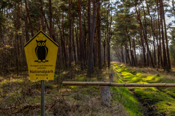 ein Hinweisschild Naturschutzgebiet vor einer Lichtung im Wald