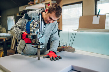 A focused worker is operating a foam cutter at his workshop.