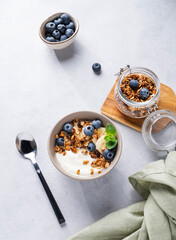 Muesli with vegetarian yogurt, banana and blueberries in a bowl on a light background. Healthy and dietary homemade granola for breakfast.