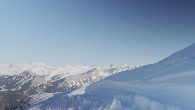 A skier approaches the edge and begins the descent of a piste in the snow-capped mountains of the Alps, France