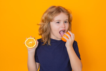 Healthy fruits for kids. Kid eat orange in studio. Studio portrait of cute child lick orange isolated on yellow background.