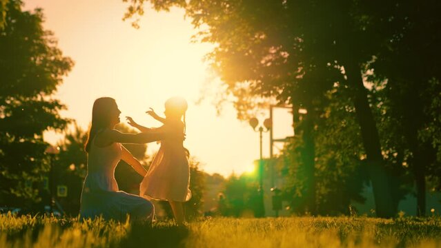 Carefree childhood, joyful embrace of child of mother. Child, daughter runs to mom, hugs her in park. Happy family. Child has fun in summer on street with mother. Family Mom, kid girl outdoors sun day
