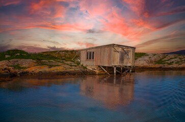 Old abandoned sea bow at sunset. The cabin is located in a rugged coastal landscape