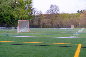 Late afternoon photo of a lacrosse goal on a synthetic turf field before a night game.
