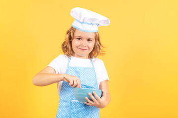 Kid chef cook with cooking bowl. Cooking children. Chef kid boy making healthy food. Portrait of little child in chef hat isolated on studio background. Kid chef. Cooking process.