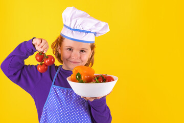 Kid cook hold tomato. Excited chef cook. Child wearing cooker uniform and chef hat preparing food, studio portrait.