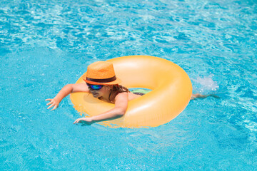 Child swim on ring floating in blue swimming pool. Inflatable ring, rest kids concept.