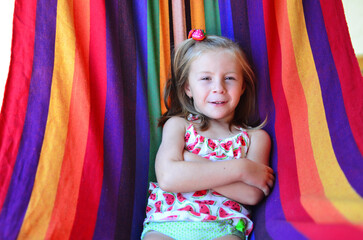 A little girl lies on a colorful hammock