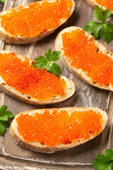 Salmon red caviar sandwiches on wooden board