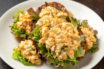 Egg salad sandwiches with greens and herbs on white plate. Healthy food.