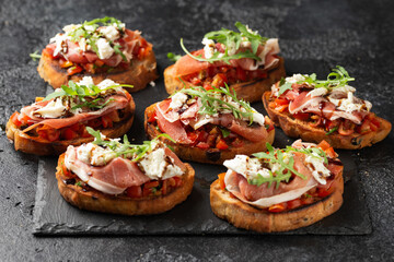 Parma ham and tomato bruschetta served on black slate with mozzarella, wild rocket leaves and balsamic vinegar