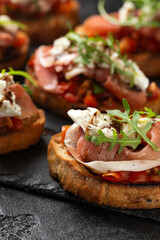 Parma ham and tomato bruschetta served on black slate with mozzarella, wild rocket leaves and balsamic vinegar