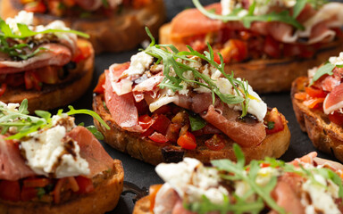 Parma ham and tomato bruschetta served on black slate with mozzarella, wild rocket leaves and balsamic vinegar