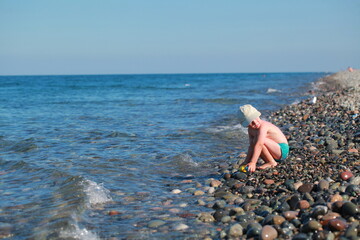 kid shoots from a water gun on the seashore . Pebble beach