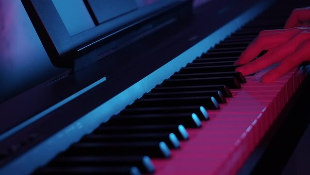 Womans hands playing piano - dramatic neon modern light, cinematic, dark key. slow motion
