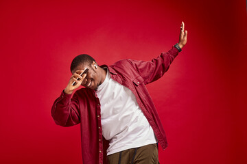 Handsome black african american man with phone dancing and rejoicing on pure red background
