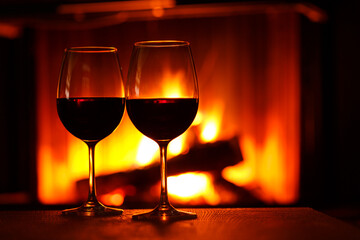 Tqo glasses of red wine next to the fireplace