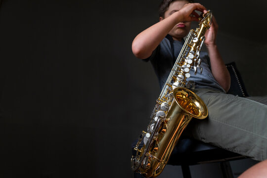 Young boy practicing playing the saxophone instrument at home
