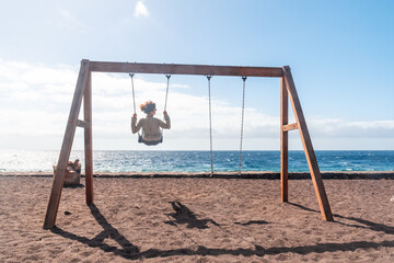 A woman on vacation swinging on a swing on the beach of the island of El Hierro. Canary Islands