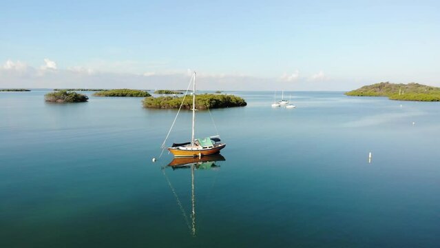 beautiful sailboat in tropical and crystalline waters with cays in the background