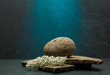 composition of beautiful stones and white small flowers on a gray background for product presentation podium background.zen stones with texture and shadows on a gray background.