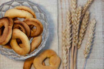 Homemade baking. Dry bagels in a glass vase on a napkin against the background of spikelets of wheat