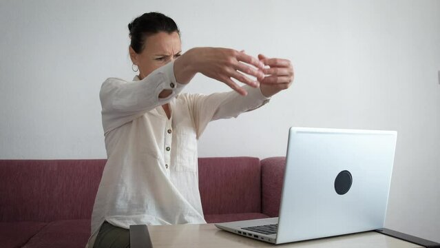 Freelancer with wrist pain indoor. An upset woman freelancer feel the sore wrist and try to makes some exercices by the computer. Generative AI