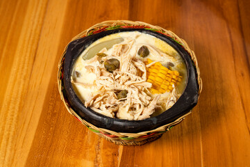 Ajiaco, traditional Colombian food, accompanied by shredded chicken, milk cream, capers, corn on the cob and potato
