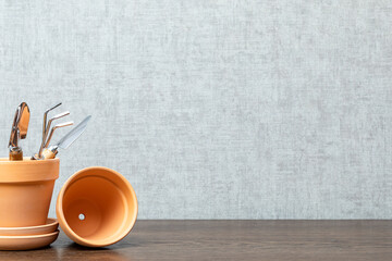 Empty ceramic pots and small gardening tools on a wooden table. The concept of transplanting indoor plants, gardening and hobbies.