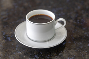 Black coffee served in white minimalist cup on dark background