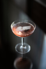 Looking down on a glass of pink champagne on a glass table by a window at sunset