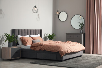 Stylish bedroom interior with comfortable bed and green houseplants