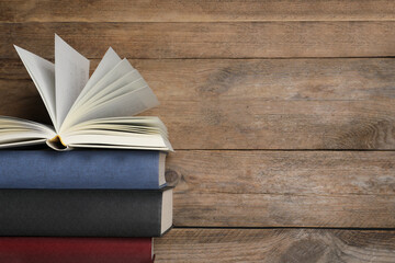 Stack of hardcover books on wooden table, space for text