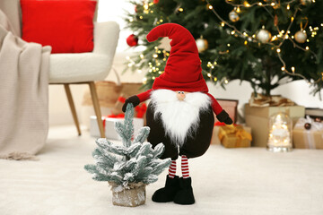 Obraz premium Funny Christmas gnome and tree on floor in room with festive decoration