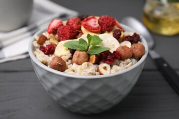 Oatmeal with freeze dried fruits, nuts and mint on grey wooden table, closeup