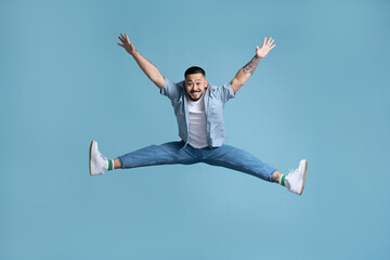 Full length portrait of positive inspired asian man jumping in air