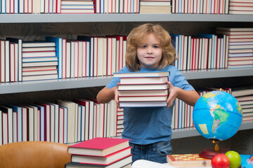 School boy with stack of books in library. School and education concept. Portrait of cute child school boy. Back to school.